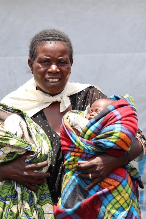 En kvinna håller två spädbarn i sina armar.