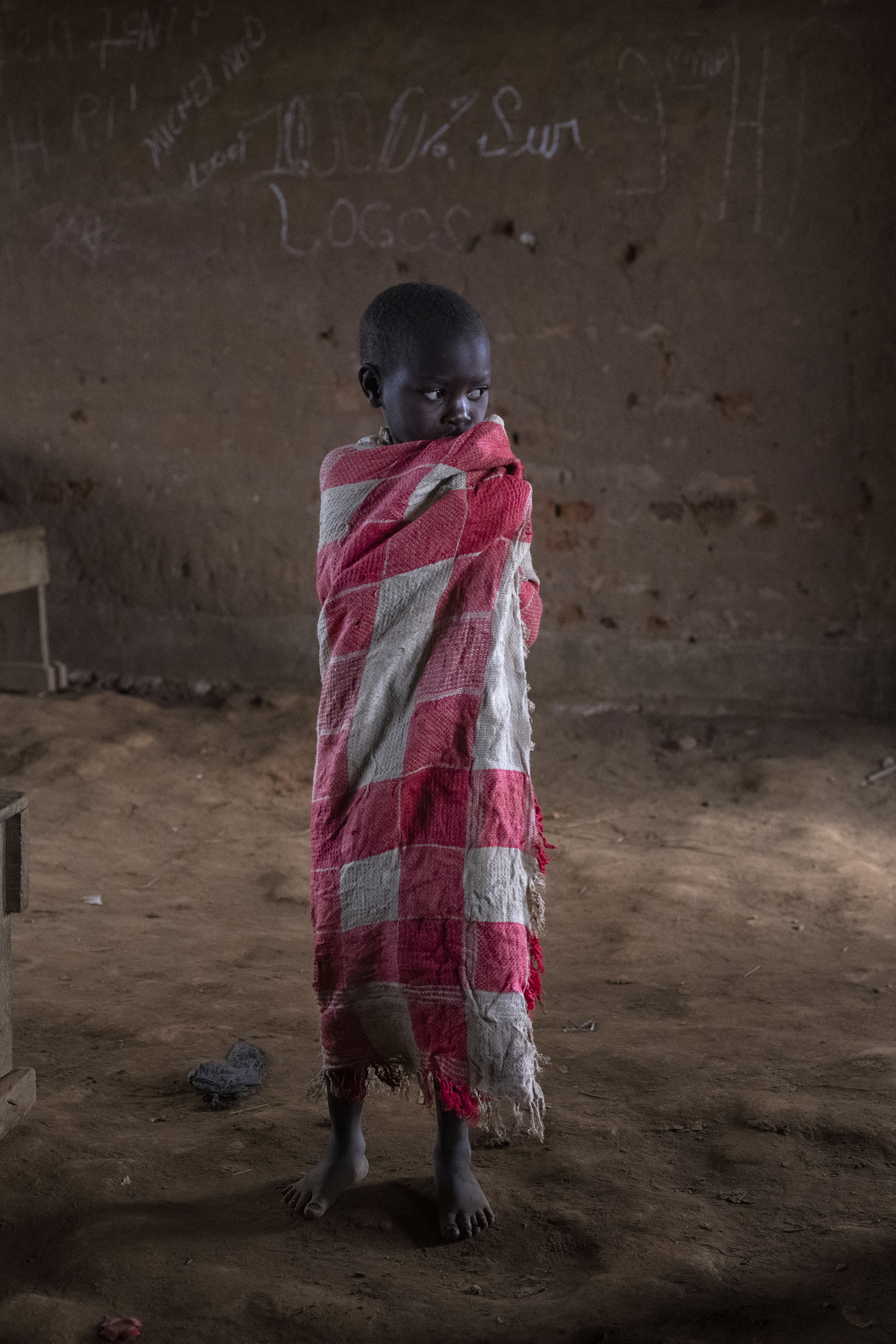 Ett litet skolbarn står ensam i ett klassrum i Kongo.