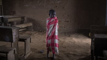 Ett litet skolbarn står ensam i ett klassrum i Kongo.