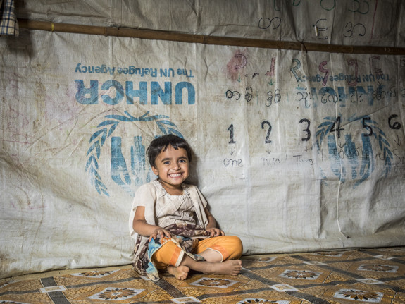 En liten flicka sitter i ett tält i Bangladesh.