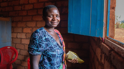 En kvinna står i ett tegelhus. Hon ler mot kameran.