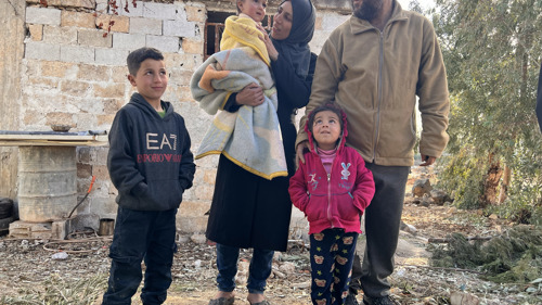 Nadim, Faten och deras barn står framför deras skadade hus i Syrien. De har varit på flykt sedan 2013 och har nyss kunnat återvända. De hoppas att kunna bygga upp sitt liv igen.