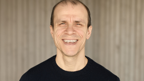 En man tittar in i kameran och ler.