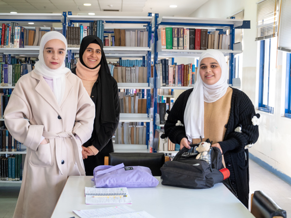 Tre kvinnliga studenter i Jordanien ler mot kameran.