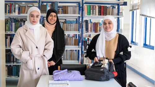 Tre kvinnliga studenter ler mot kameran.