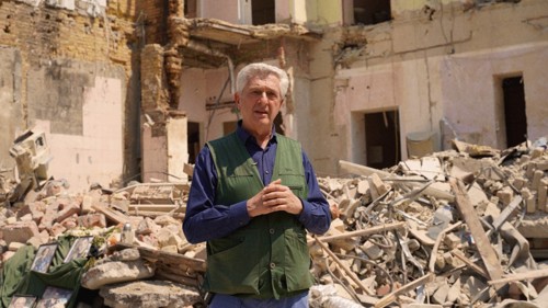 Filippo Grandi står i ruinerna av ett förstört hus i Ukraina.