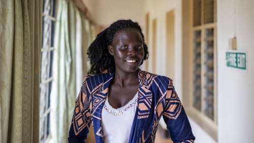 En kvinna tittar in i kameran och ler.