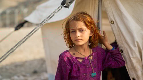En flicka på flykt återvänder hem från Pakistan till Afghanistan. Här står hon utanför ett UNHCR-tält i Afghanistan nära gränsen till Pakistan.