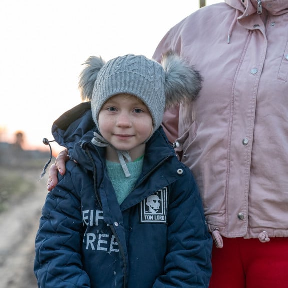 En flicka i Ukraina står med sin mamma på en väg.