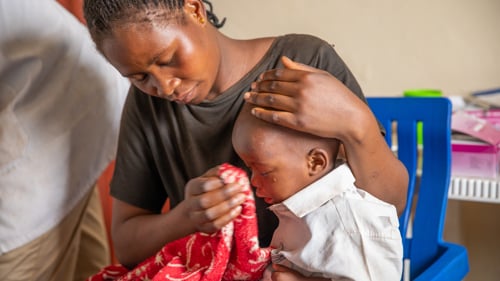 Chancelline, som har tvingats på flykt från Kongo, får hjälp för sin lilla son på UNHCR:s vårdcentral i Musenyi, Burundi. Pojken fick feber kort efter att familjen anlänt till flyktingområdet i mars 2025. Musenyi har tagit emot många människor som först kom till gränsen vid Rugombo.