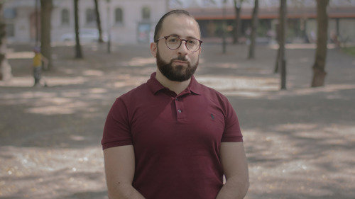 En man i mörkröd tröja står på en grusväg.