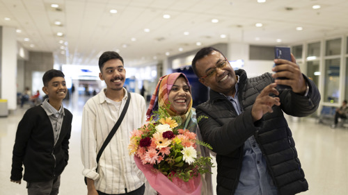 En rohingya-familj återförenas på flygplatsen, de ler in i en kamera.