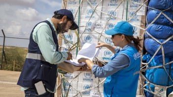 En man och en kvinna i UNHCR-kläder prickar av en checklista.