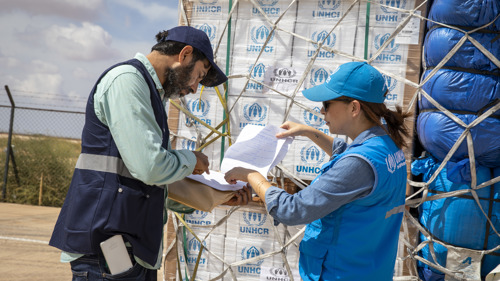 UNHCR-personal checkar av en lista vid en fraktpall med nödhjälpsartiklar.
