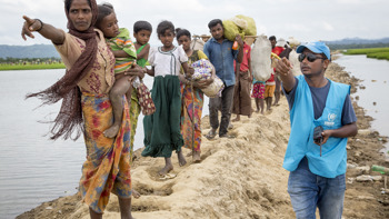 Människor flyr över sanddynor från Myanmar till Bangladesh.