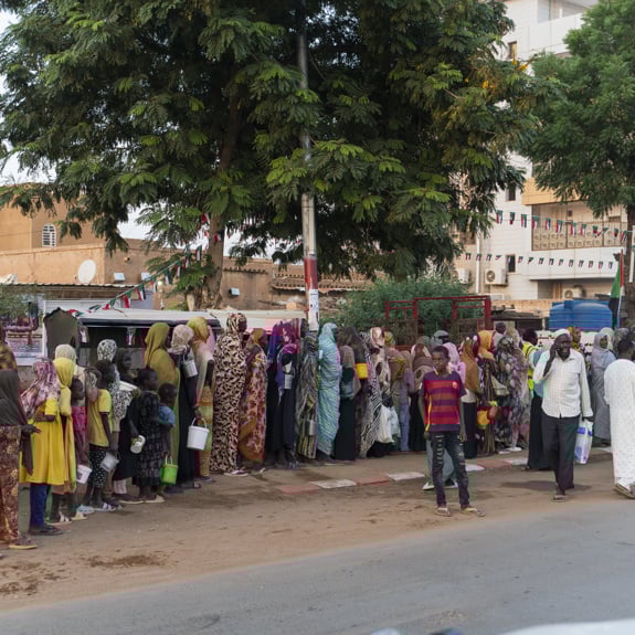 Människor som flytt kriget står i en kö för att få matutdelning.