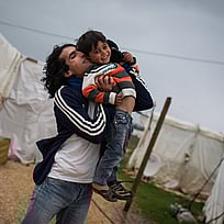 Två bröder på flykt från Syrien kramas i ett tältläger i Libanon.