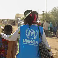 UNHCR-personal håller armen runt axlarna på ett barn.