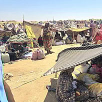 Människor som flytt kriget i Sudan sitter utspridda på marken.