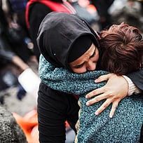 En syrisk flykting som korstat Egeiska havet från Turkiet i en ranglig båt kramar sin son efter att ha nått trygghet på ön Lesbos i Grekland.