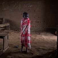 Ett litet skolbarn står ensam i ett klassrum i Kongo.