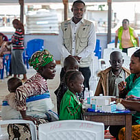 En familj sitter runt ett bord, tillsammans med UNHCR-medarbetare.
