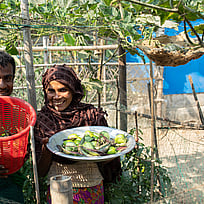 En man och en kvinna visar upp sina odlade grönsaker för fotografen.