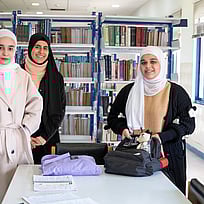 Tre kvinnliga studenter i Jordanien tittar mot kameran och ler.