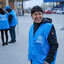 En kvinna med UNHCR-väst tittar in i kameran.