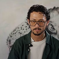 Ett foto på Hadi, som sitter framför en vägg.