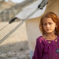 En flicka på flykt återvänder hem från Pakistan till Afghanistan. Här står hon utanför ett UNHCR-tält i Afghanistan nära gränsen till Pakistan.
