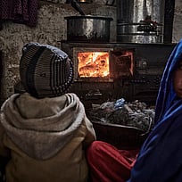Två barn sitter framför en värmekamin.