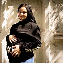 En gravid ukrainsk kvinna tittar mot kameran och håller sig varsamt om magen.