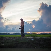 Kvinna som står på ett fält med en blå och solig himmel