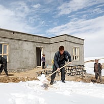 En familj röjer snö framför sitt nya hus i en bergsby i Afghanistan.