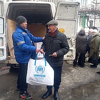 UNHCR lämnar över förnödenheter till en äldre man i Kherson, Ukraina.