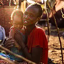 En kvinna från Sudan håller sin dotter i famnen i ett flyktingläger i Sydsudan.