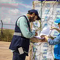 En man och en kvinna i UNHCR-kläder prickar av en checklista.