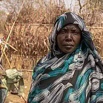 40-åriga Maha står bredvid sitt boende i ett flyktingläger i nordvästra Etiopien. Hon, hennes barn och mamma har flytt undan våldet i Sudan. Foto: UNHCR/Tiksa Negeri