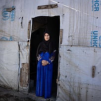 Den syriska flyktingen Shadia Mohammad Jesm, 50 år, står vid dörren till sitt tält i flyktinglägret Jasmine i Saadnayel, Libanon, där hon har bott de senaste fem åren. "Det är väldigt osäkert i Syrien just nu", säger Shadia. "Vi vill återvända, men vi är rädda. Jag önskar bara det bästa för mitt land." Foto: UNHCR/Ximena Borrazas