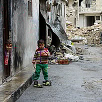 En liten pojke står i ruinerna i Aleppo. Hur du kan hjälpa under Ramadan.