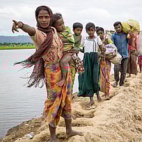 Människor flyr över sanddynor från Myanmar till Bangladesh.