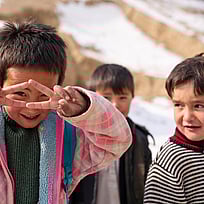 Tre barn poserar för kameran i snön i norra Afghanistan.