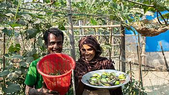 En man och en kvinna visar upp sina odlade grönsaker för fotografen.