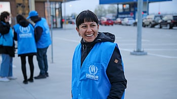 En kvinna med UNHCR-väst tittar in i kameran.