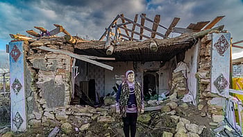 En ukrainsk kvinna står mitt i rasmassorna av sitt tidigare hus.