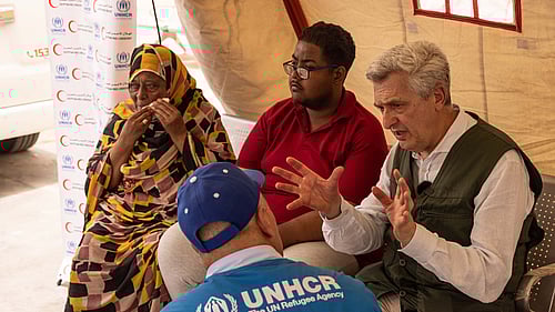 Fyra personer samtalar. En av dem har en UNHCR-väst på sig.