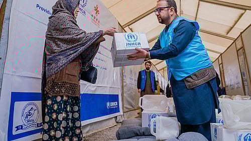 En UNHCR-medarbetare lämnar över en kartong med förnödenheter i Afghanistan.