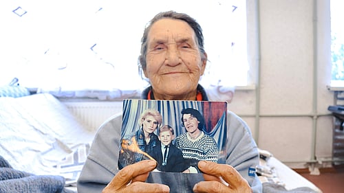 Nina visar upp en bild på sig själv, hennes dotter och barnbarn i sovsalen i Mezhova.