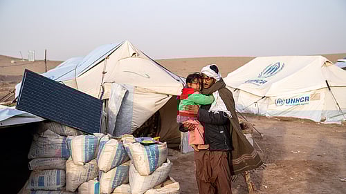 En pappa och barn står utanför sitt tält efter en jordbävning drabbat Afghanistan.
